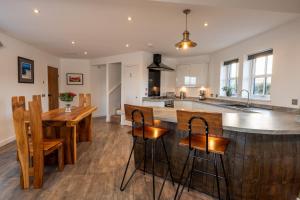an open kitchen with a wooden island and wooden stools at Dark Skye Cottage in Broadford