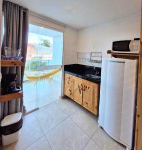 a kitchen with a white refrigerator and a window at MSFlats Paripueira Praia Wifi Ar Cozinha e Varanda Nascente c Rede in Paripueira