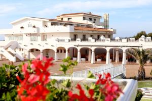 a large white building with red flowers in front of it at Acqua di Mare Hotel e Resort in Marina di Sorso
