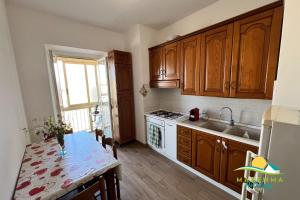a kitchen with wooden cabinets and a table and a sink at Maremma Holidays-Gardenia Apartment in Follonica