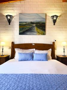 1 cama con almohadas azules y una pintura en la pared en Barranco da Fonte, en Chabouco