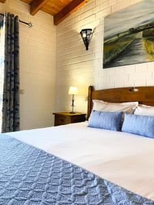 1 dormitorio con 1 cama blanca grande con almohadas azules en Barranco da Fonte, en Chabouco