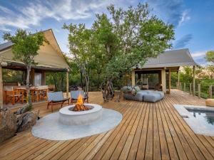 une terrasse en bois avec un foyer extérieur et une maison dans l'établissement Bushveld Bivouac Private Camp, à Mica