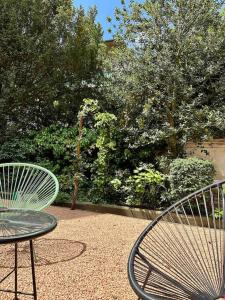 two chairs and a table in a yard with trees at Maison Fitzgerald in Vichy