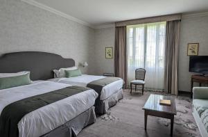 une chambre d'hôtel avec deux lits et un canapé dans l'établissement Relais de Margaux - Hôtel & Spa, à Margaux