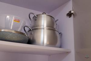 two pots and pans on a shelf in a kitchen at Charming Rooftop Apartments with Great view & Free Strong Wi-Fi - 40percent Long-stay Disc- Red Lotus Oasis in Accra