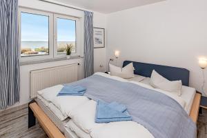 a bedroom with a large bed with two windows at Aquarius Ferienwohnung Usedom in Loddin