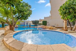 a swimming pool in a resort with trees and a building at Apartamento Mandarín Playamarina 2 in Orihuela