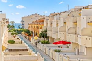 a city street with white buildings and a red umbrella at Apartamento Mandarín Playamarina 2 in Orihuela