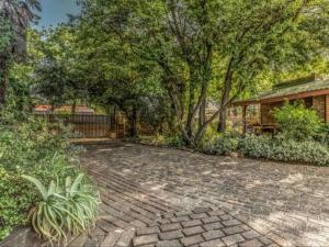 une terrasse en briques avec des arbres et une maison dans l'établissement Lesedi Guesthouse Middleburg, à Middelburg