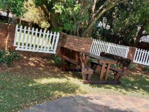 un banc en bois à côté d'une clôture blanche dans l'établissement Lesedi Guesthouse Middleburg, à Middelburg