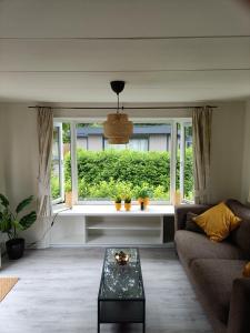 uma sala de estar com um sofá e uma janela em Huisje Veluwe bij Putten aan het Speuldersbos em Putten