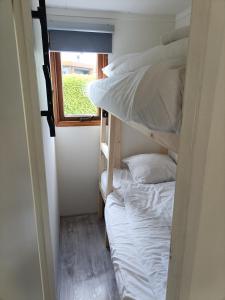 2 Etagenbetten in einem kleinen Zimmer mit Fenster in der Unterkunft Huisje Veluwe bij Putten aan het Speuldersbos in Putten