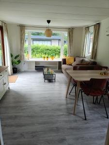 ein Wohnzimmer mit einem Sofa und einem Tisch in der Unterkunft Huisje Veluwe bij Putten aan het Speuldersbos in Putten