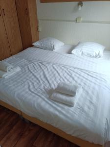 ein großes weißes Bett mit zwei Handtüchern darauf in der Unterkunft Huisje Veluwe bij Putten aan het Speuldersbos in Putten