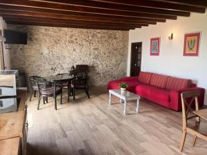 ein Wohnzimmer mit einem roten Sofa und einem Tisch in der Unterkunft Vivelorural Abuela María 2, a place for families in San Bartolomé de Tirajana