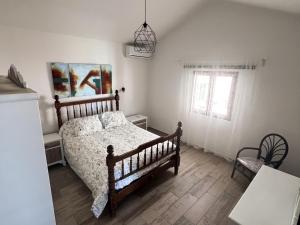 ein Schlafzimmer mit einem Bett und einem Stuhl und einem Fenster in der Unterkunft Vivelorural Abuela María 2, a place for families in San Bartolomé de Tirajana