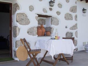 einen Tisch und Stühle vor einer Steinmauer in der Unterkunft Vivelorural Abuela María 1, chill garden pool in San Bartolomé de Tirajana