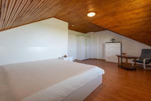 a bedroom with a white bed and a wooden ceiling at Birutės Vila in Palanga