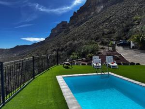 サン・バルトロメにあるVivelorural Abuela María 3, garden & poolの緑の芝生と山のあるプール