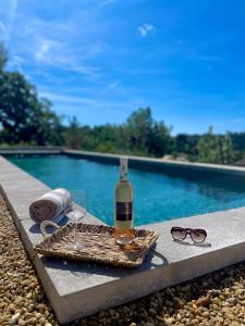 eine Flasche Wein und Gläser neben dem Pool in der Unterkunft Villa: piscine, sauna, fitness, à pied du village in Valbonne