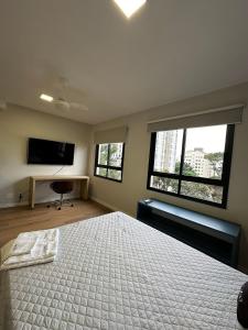 um quarto com uma cama e uma televisão e duas janelas em TrevizZo N.urban Pinheiros em São Paulo