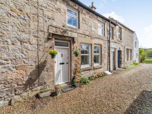 a brick house with a white door on a cobblestone street at 2 Bed in Rothbury 87902 in Rothbury