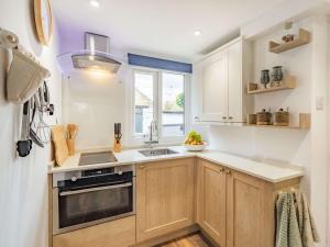 eine Küche mit Holzschränken, einem Waschbecken und einem Fenster in der Unterkunft 2 Bed in Rothbury 87902 in Rothbury