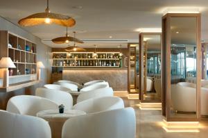 a restaurant with white chairs and a bar at Dom Jose Beach Hotel (Plus) in Quarteira