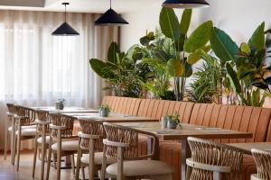 uma fila de mesas e cadeiras num restaurante com plantas em Dom Jose Beach Hotel (Plus) em Quarteira