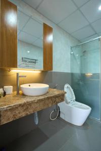 ein Badezimmer mit einem Waschbecken, einem WC und einem Spiegel in der Unterkunft Pooh House 6 - Back Beach apartment in Vũng Tàu