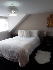 a bedroom with a white bed and a chandelier at Derry City center townhouse in Derry Londonderry