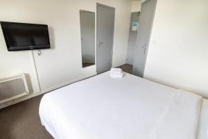 a bedroom with a white bed and a tv at Kyriad Direct Auxerre - Appoigny in Appoigny
