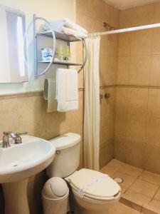 y baño con aseo blanco y lavamanos. en Angeles Suites & Hotel en Veracruz
