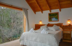 um quarto com uma cama e uma grande janela em Apart Hotel del Pellin em San Martín de los Andes
