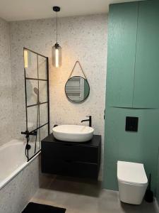a bathroom with a sink and a tub and a toilet at Mieszkanie z basenem i siłownią Bronowicka in Szczecin