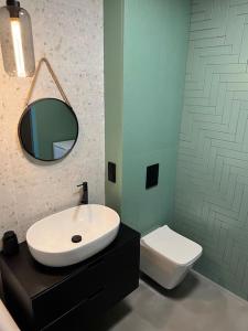 a bathroom with a sink and a mirror and a toilet at Mieszkanie z basenem i siłownią Bronowicka in Szczecin +8 photos