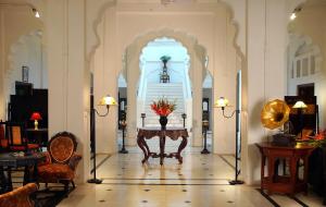 un pasillo con mesa y sillas en un edificio en WelcomHeritage Bal Samand Lake Palace en Jodhpur