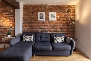 a blue couch in a room with a brick wall at Luxury Apartment Woodsmill View - on the river - with balcony - Recently refurbished in York