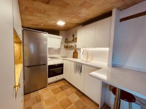 una cucina con armadi bianchi e frigorifero in acciaio inossidabile di Penthouse on Passeig del Mar de Tamariu Large Terrace Free WiFi Platja a Tamariu