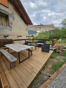a wooden deck with a picnic table and an umbrella at Appartement Acolin in Briançon