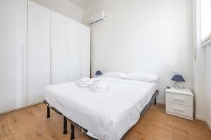 ein weißes Schlafzimmer mit einem Bett und einem Nachttisch in der Unterkunft Deiva Marina Sea House! Functional Apartment in Deiva Marina