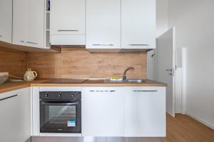 eine Küche mit weißen Schränken und einem schwarzen Backofen in der Unterkunft Deiva Marina Sea House! Functional Apartment in Deiva Marina + 7 Fotos