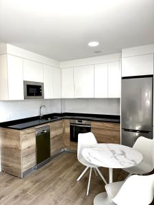 una cucina con mobili bianchi, tavolo e sedie di Apartamento la Muralla 1D a Aguilar de Campóo
