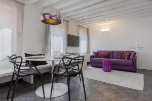ein Wohnzimmer mit einem Tisch und einem lila Sofa in der Unterkunft Tadomo - Corte del Cafetier in Venedig
