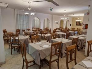 a dining room with tables and chairs and chandeliers at Hotel Caruso in Rimini