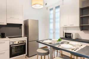a kitchen with white cabinets and a table with chairs at Appartamento vicino Milano, Como e MXP in Busto Arsizio
