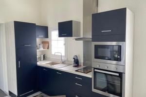 cocina con armarios azules, fregadero y microondas en Charming house with garden in the heart of Saint Martin, en Saint-Martin-de-Ré