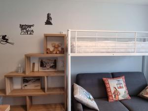 a bedroom with a bunk bed and a couch at Studio centre Super-Besse in Besse-et-Saint-Anastaise