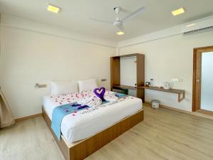 Un dormitorio con una cama grande con una cinta morada. en Lagoon Villa Thoddoo en Thoddoo